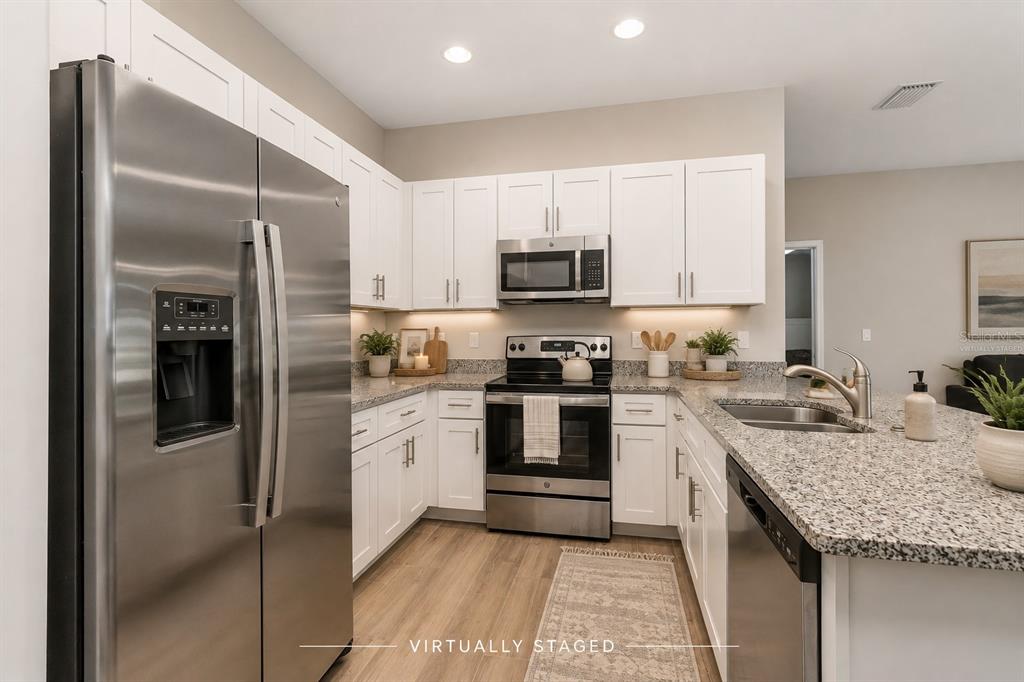 A kitchen with white cabinets, stainless steel appliances, and granite countertops in a staged home — 2841 NW 45TH PLACE, CAPE CORAL, FL