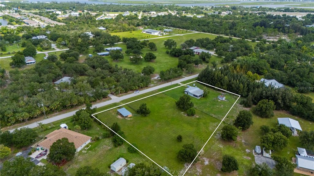 An aerial view shows a house and outbuilding on a large, grassy, fenced-in lot — 5380 SABAL PALM LANE, PUNTA GORDA, FL