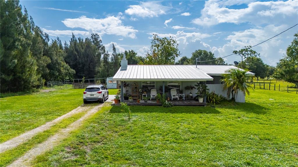 A white house with a metal roof and a front porch sits on a lawn — 5380 SABAL PALM LANE, PUNTA GORDA, FL