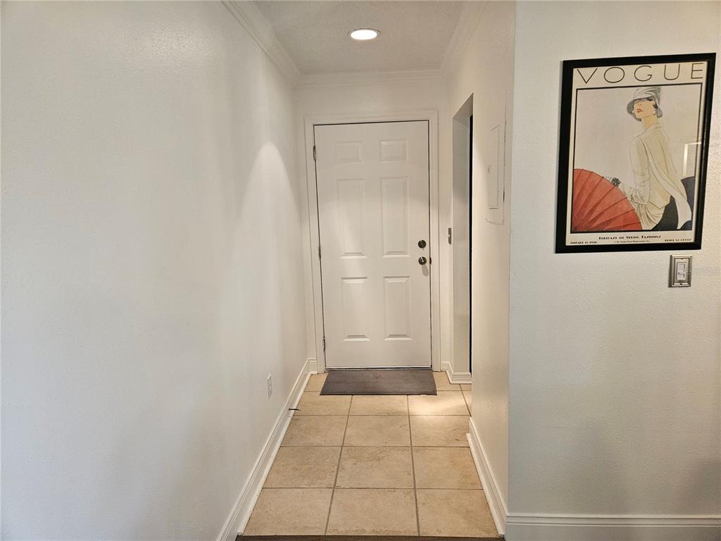 An entryway features a white door, tiled flooring, and a framed Vogue poster on the wall — 1737 PARAKEET WAY UNIT 2, SARASOTA, FL