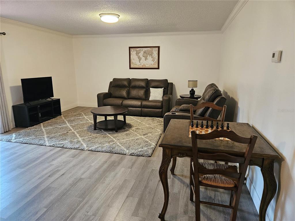 A living room features dark leather sofas, a round coffee table, and a patterned rug — 1737 PARAKEET WAY UNIT 2, SARASOTA, FL