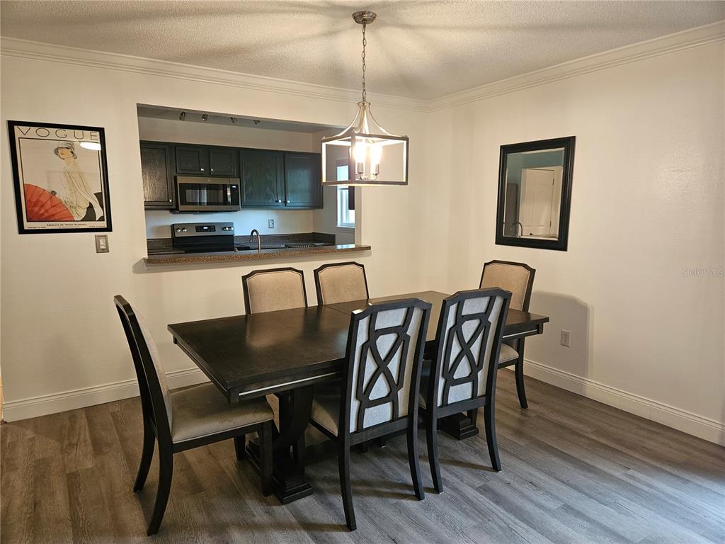 A dining room features a dark wood table with six chairs and a pendant light — 1737 PARAKEET WAY UNIT 2, SARASOTA, FL