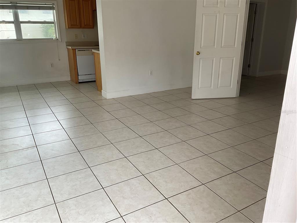 An interior view of a room with light-colored floor tiles and an open kitchen area — 2121 LAKEVIEW DRIVE, SEBRING, FL