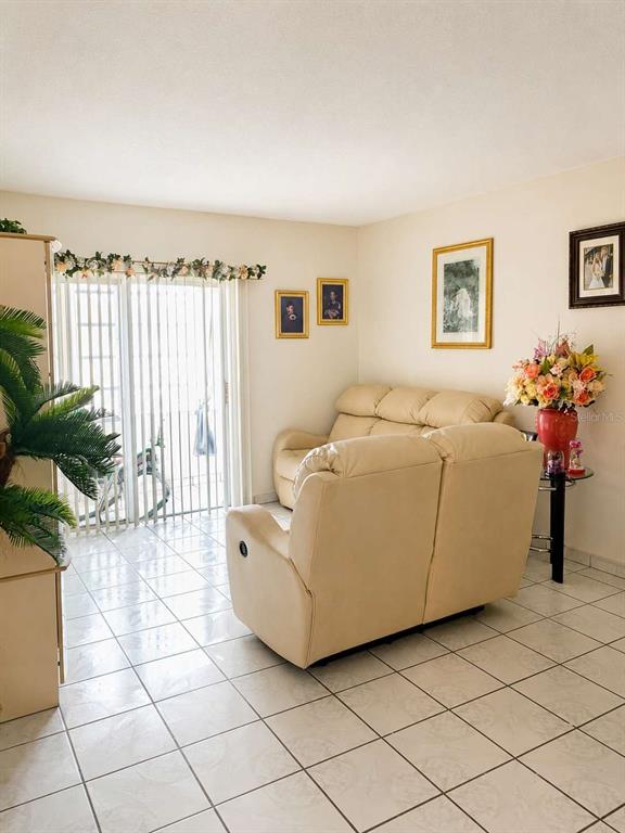 A living room features light-colored tile flooring, a beige loveseat, and a sliding glass door — 110 ROYAL PALM ROAD UNIT 208, HIALEAH GARDENS, FL