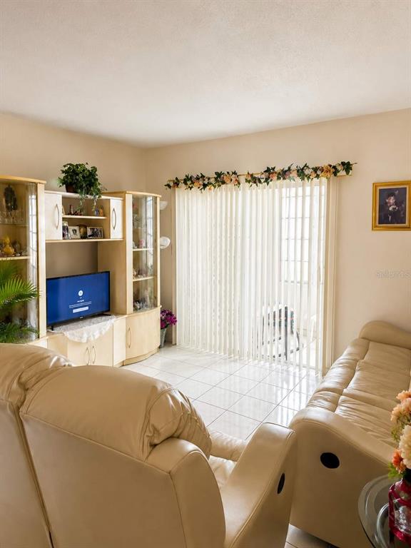 A living room features light-colored leather furniture, a media center, and vertical blinds on windows — 110 ROYAL PALM ROAD UNIT 208, HIALEAH GARDENS, FL
