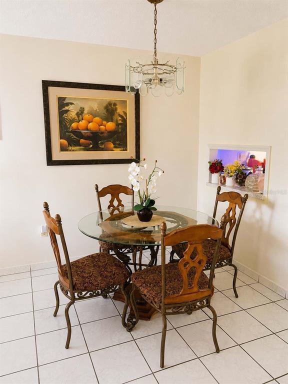 A dining area features a glass-topped table, four chairs, a chandelier, and wall art — 110 ROYAL PALM ROAD UNIT 208, HIALEAH GARDENS, FL