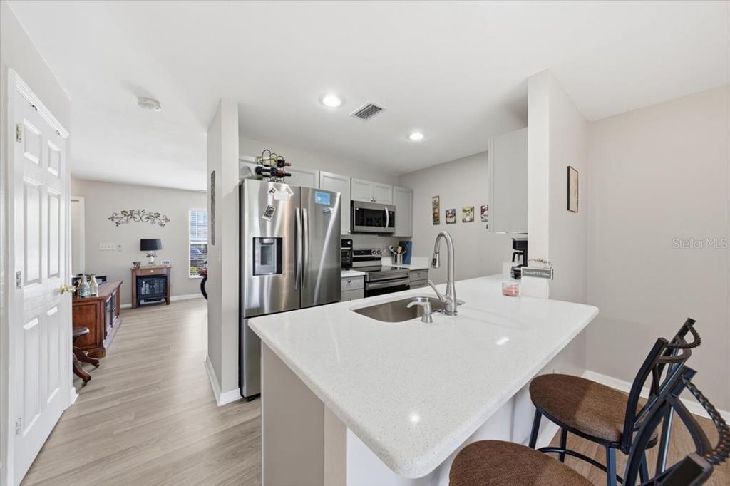A kitchen features a white quartz island, stainless steel appliances, and light wood-look flooring — 5503 67TH AVENUE N UNIT 18, PINELLAS PARK, FL