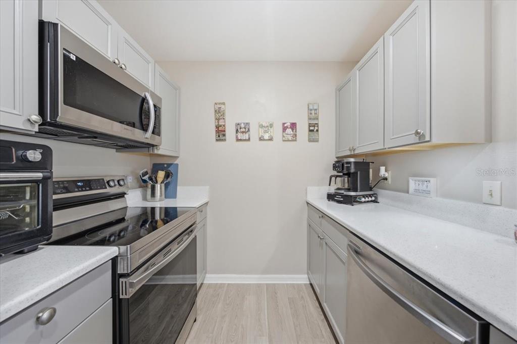 A galley kitchen features gray cabinets, stainless steel appliances, and white countertops — 5503 67TH AVENUE N UNIT 18, PINELLAS PARK, FL
