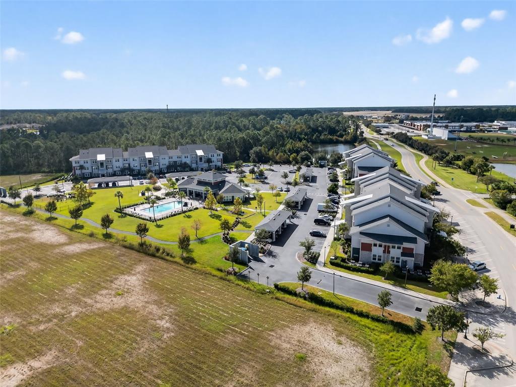 An aerial view shows a multi-building apartment complex with a pool and parking lots — 890 CENTRAL AVENUE UNIT E102, PALM COAST, FL