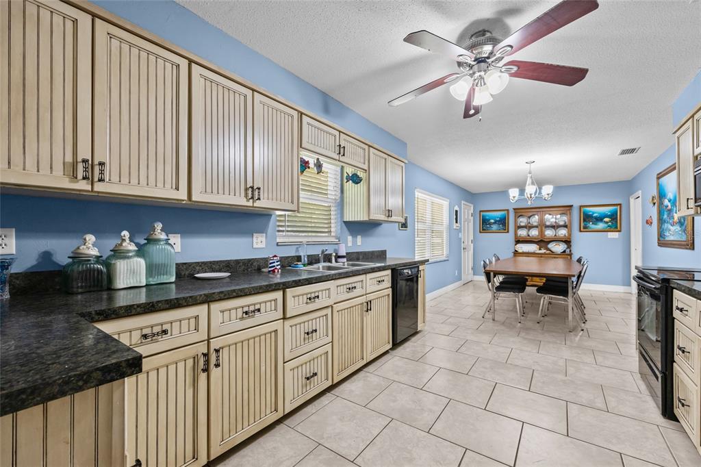 A kitchen with light-colored beadboard cabinets, dark countertops, and an adjacent dining area — 6417 BAKER ROAD, KEYSTONE HEIGHTS, FL
