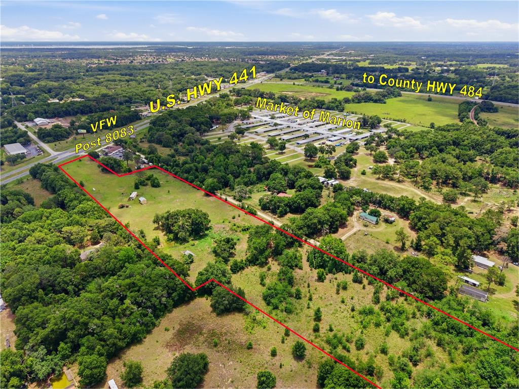 An aerial view shows a large, grassy, rectangular plot of land outlined in red — 12630 U.S. 441, BELLEVIEW, FL