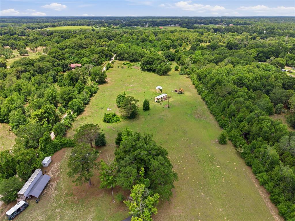 An aerial view shows a large, grassy rural lot with a mobile home and outbuildings — 12630 U.S. 441, BELLEVIEW, FL