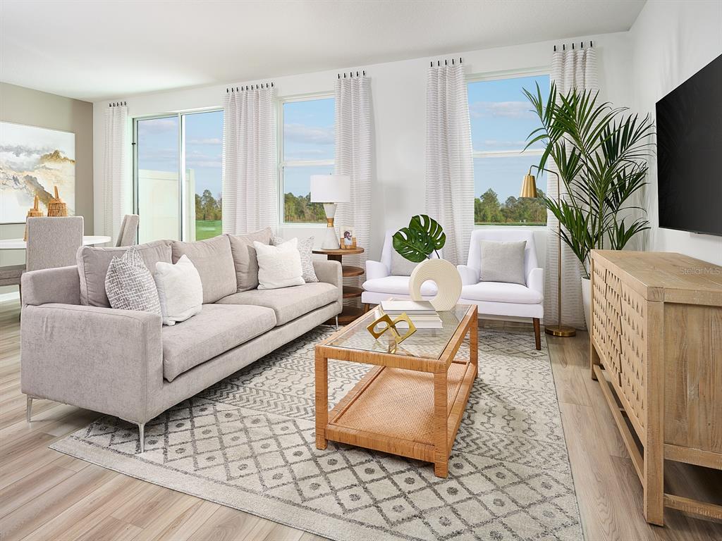 A living room features a grey sofa, a glass-topped rattan coffee table, and two white chairs — 16266 BIRD OF PARADISE AVENUE, CLERMONT, FL
