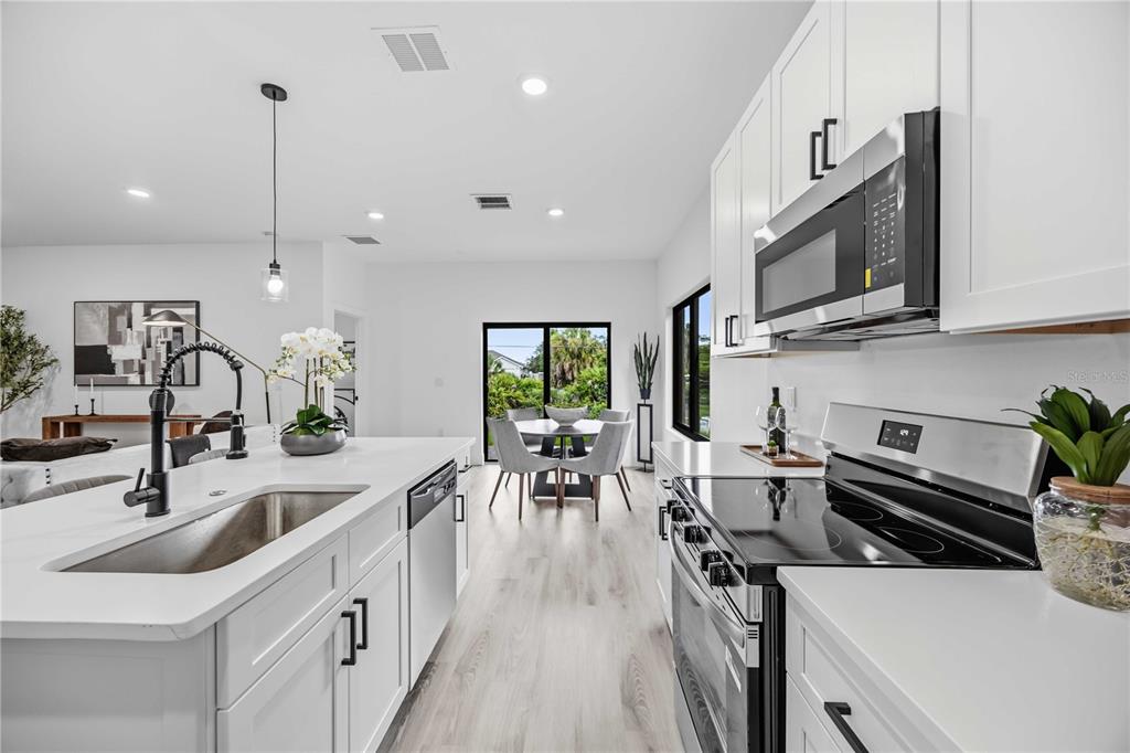 A modern kitchen features white cabinetry, a central island with a sink, and stainless appliances — 8533 LANCELOT AVENUE, NORTH PORT, FL