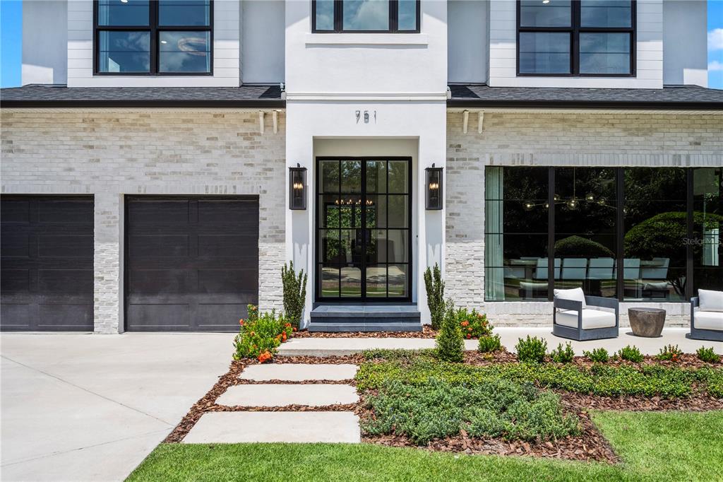 A modern two-story house features a white brick exterior, dark garage doors, and a glass-paned entryway — 751 PANSY AVENUE, WINTER PARK, FL