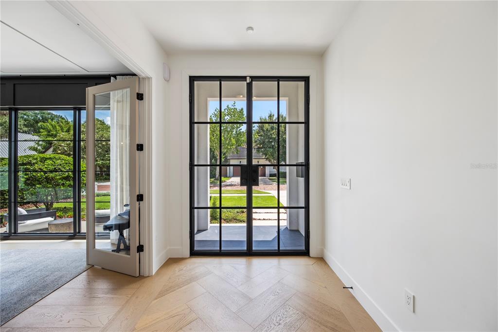 An entryway features herringbone wood floors, white walls, and black-framed glass double doors — 751 PANSY AVENUE, WINTER PARK, FL
