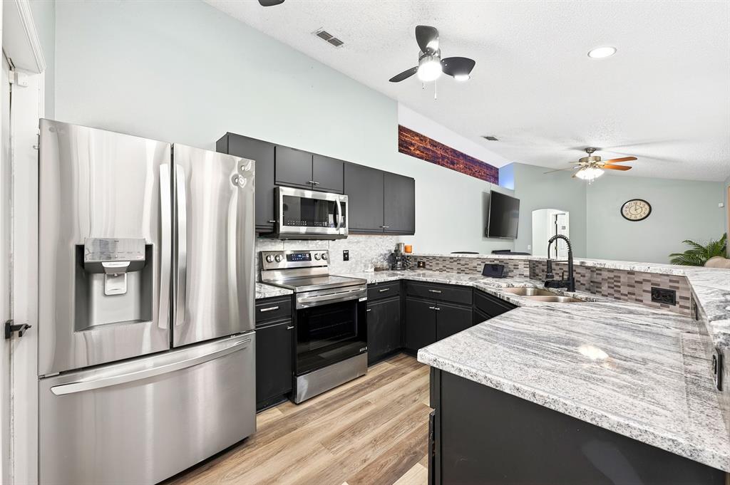 A kitchen features dark cabinets, stainless steel appliances, and granite countertops with a breakfast bar — 3147 UTAH DRIVE, DELTONA, FL