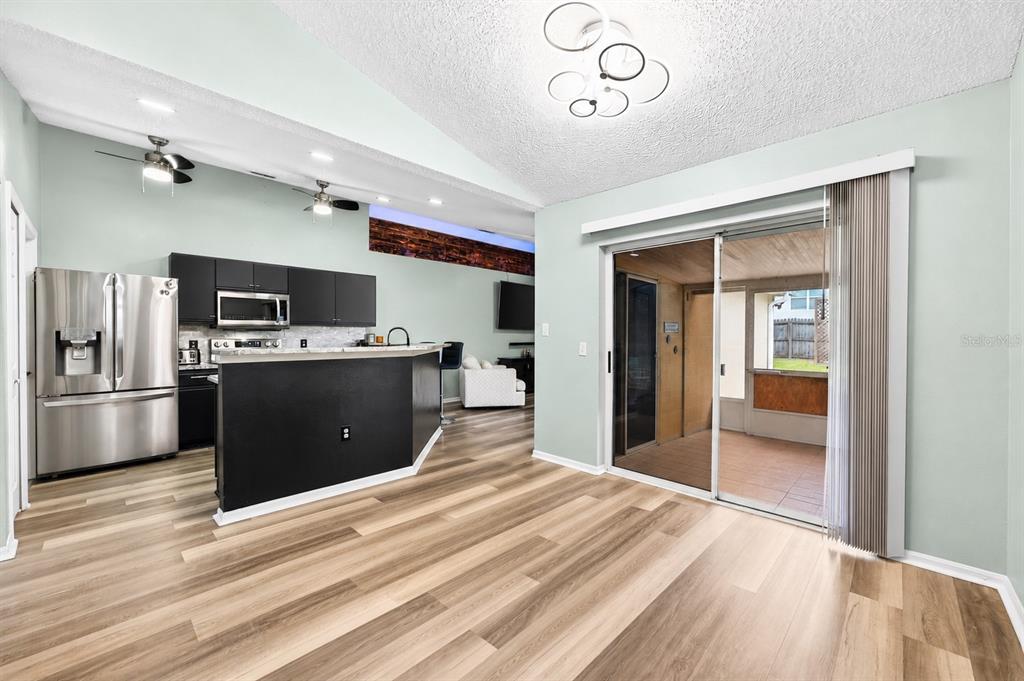 A kitchen with dark cabinets and a breakfast bar opens into a living area — 3147 UTAH DRIVE, DELTONA, FL