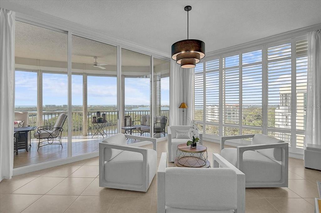 A sunlit living room features white armchairs, a tiered pendant light, and floor-to-ceiling windows — 401 N POINT ROAD UNIT 1001, OSPREY, FL