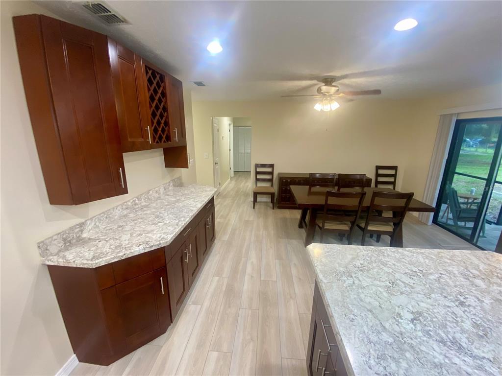 A kitchen with dark wood cabinets, marble-patterned countertops, and an adjacent dining area — 660 SUNDANCE TRAIL, WIMAUMA, FL