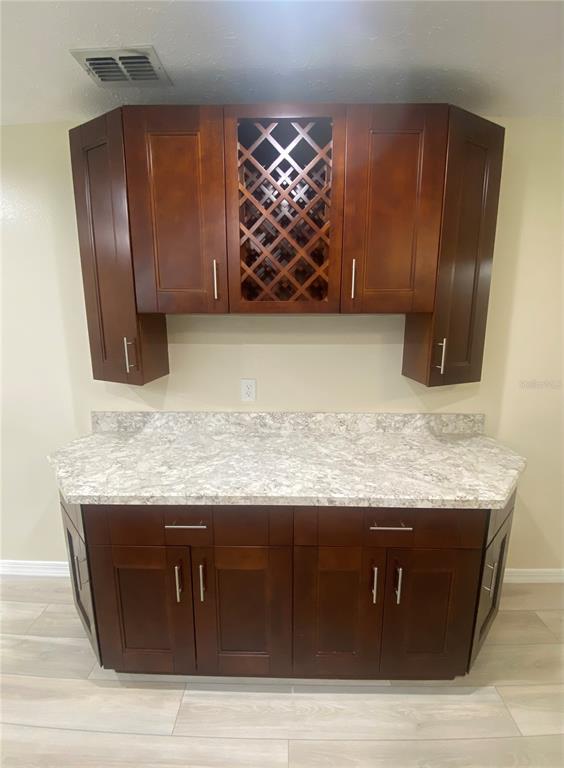 A kitchen wet bar features dark wood cabinets, a wine rack, and a stone countertop — 660 SUNDANCE TRAIL, WIMAUMA, FL