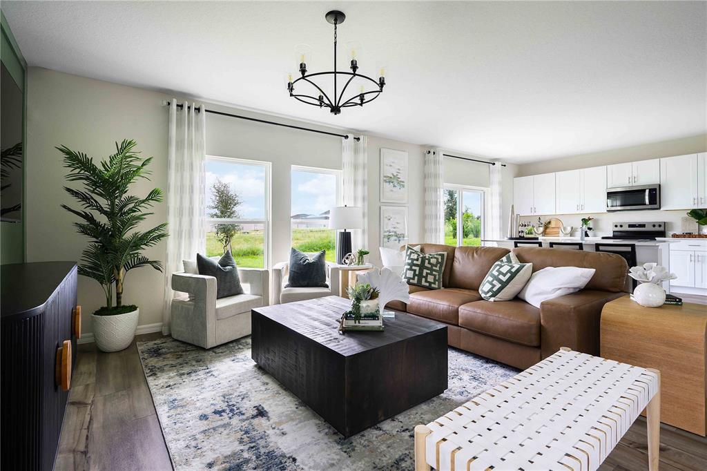 A living room with a brown leather sofa, dark coffee table, and open-concept kitchen — 36552 SAGEMOOR DRIVE, ZEPHYRHILLS, FL