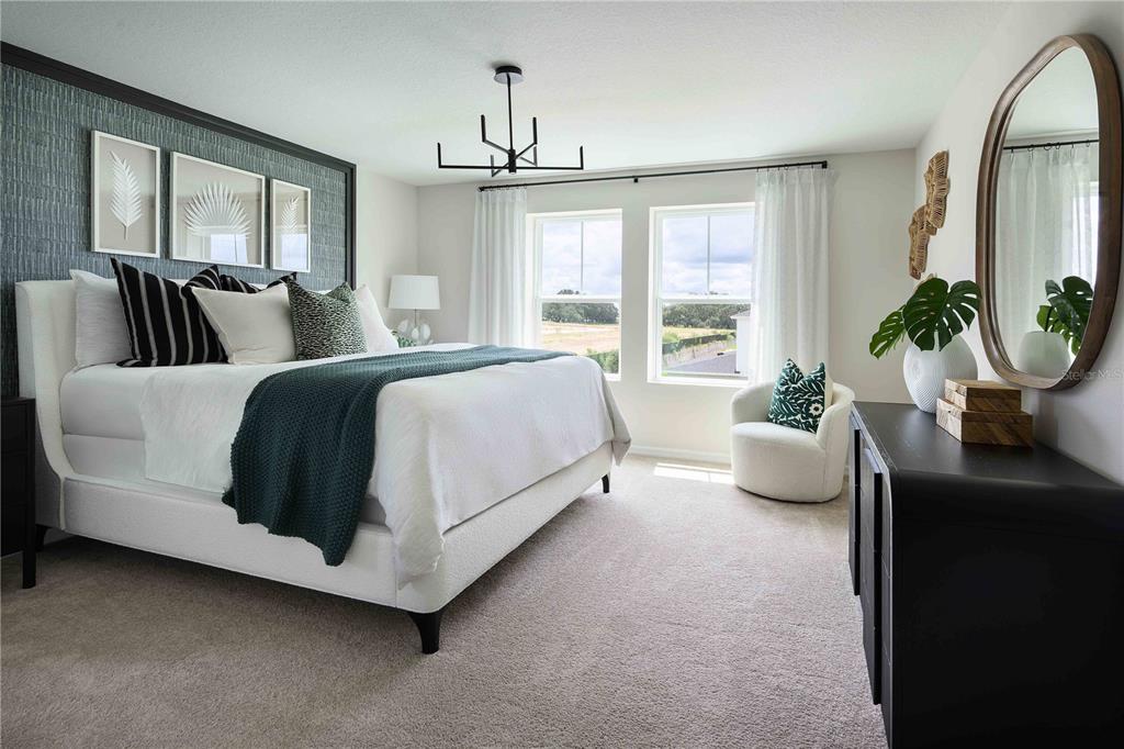 A bedroom features a white bed, a dark accent wall, and a large oval mirror — 36552 SAGEMOOR DRIVE, ZEPHYRHILLS, FL