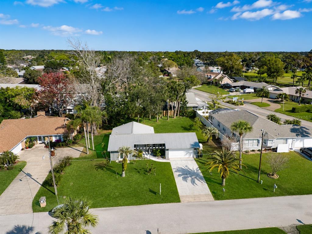 An aerial view shows a single-story house with a metal roof and a large lawn — 101 SEA STREET, NEW SMYRNA BEACH, FL