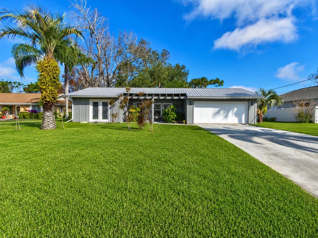 A single-story gray house with a metal roof, a two-car garage, and a palm tree — 101 SEA STREET, NEW SMYRNA BEACH, FL