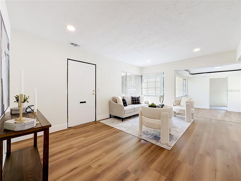 A living room features light wood-look flooring, white walls, and a seating area with a rug — 948 NE 6TH ST, OCALA, FL