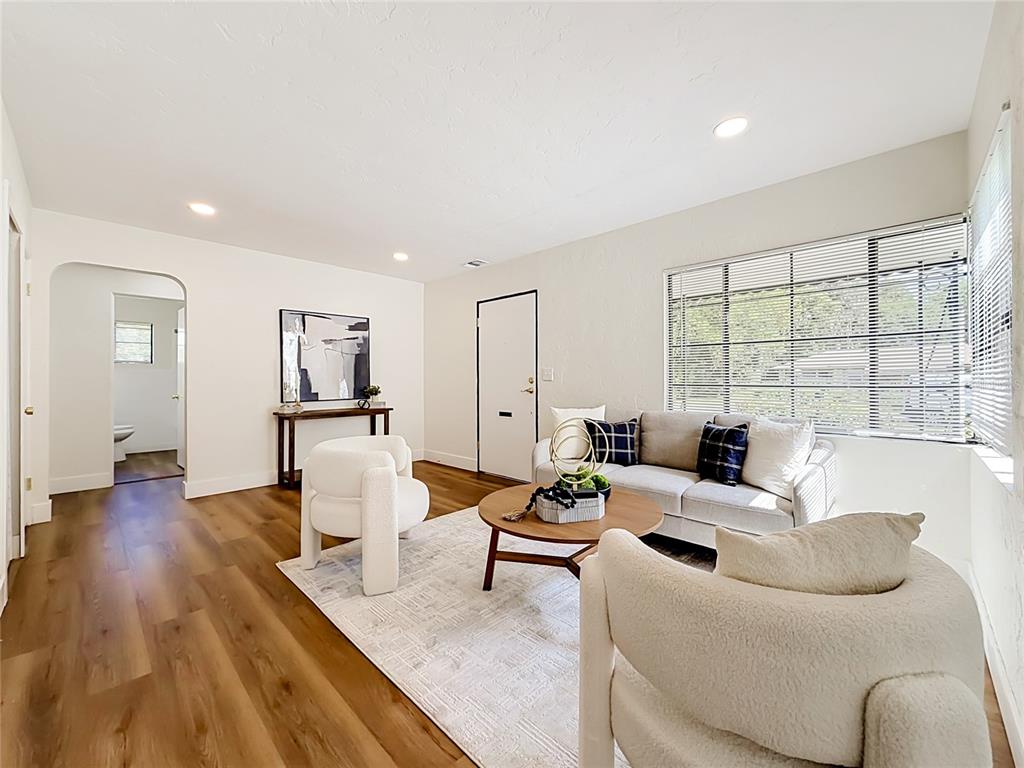 A living room features white walls, wood-look flooring, two cream armchairs, and a grey sofa — 948 NE 6TH ST, OCALA, FL