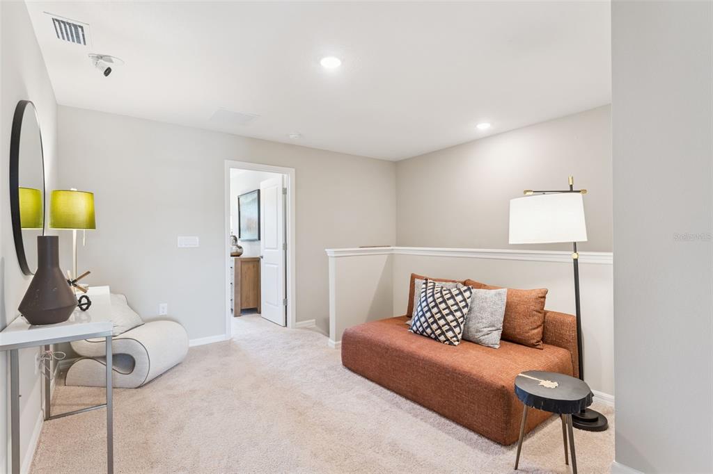 A carpeted loft area features a brown sofa, a floor lamp, and a modern chair — 2303 RED PINE COURT, EUSTIS, FL