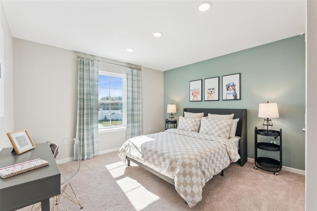 A bedroom features a bed with checkered bedding, a desk, and a green accent wall — 2303 RED PINE COURT, EUSTIS, FL
