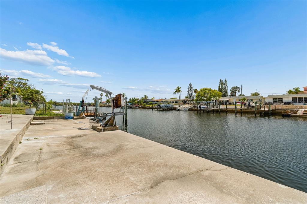 A concrete seawall overlooks a canal with boat docks and residential properties in the background — 12617 4TH ISLE, HUDSON, FL