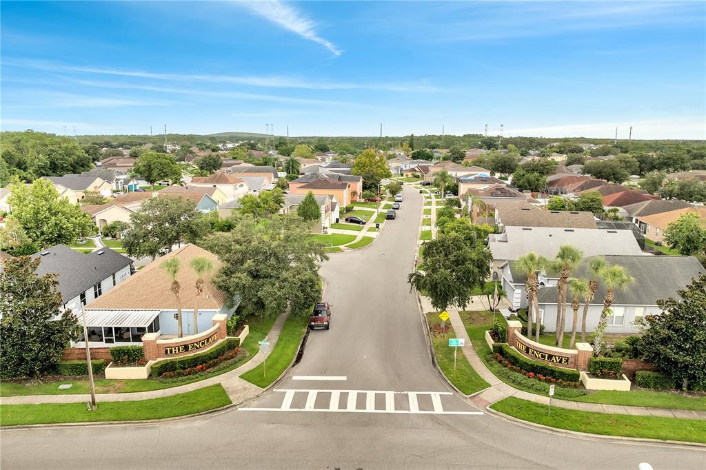 An aerial view shows the entrance to a residential neighborhood with two stone monument signs — 3030 HOLLAND DRIVE, ORLANDO, FL