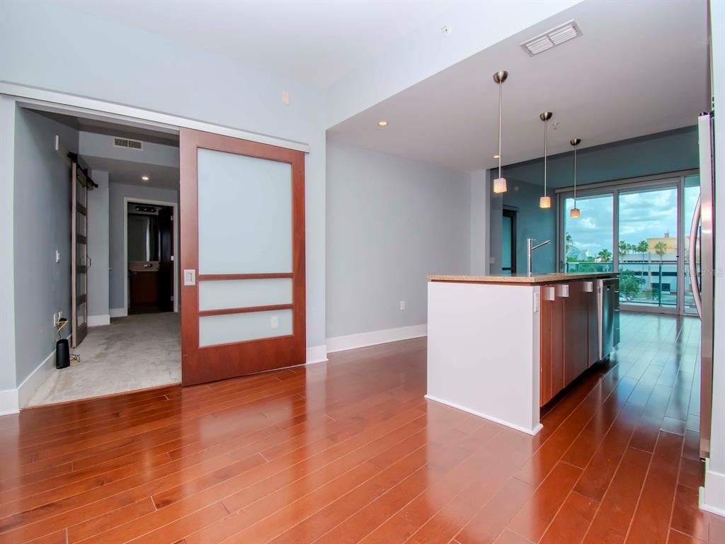 A kitchen island with pendant lights sits on hardwood floors near a sliding glass door — 912 CHANNELSIDE DRIVE UNIT 2311, TAMPA, FL