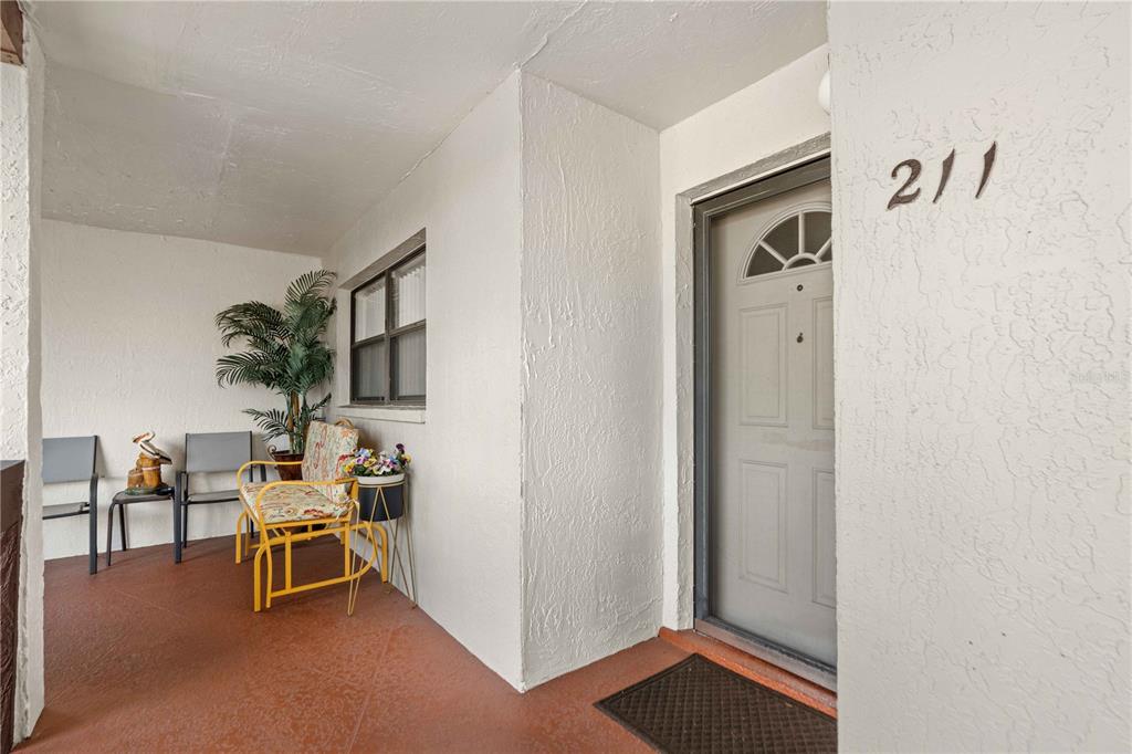 A living room features beige leather sofas, a coffee table, and a desk area — 7623 RADCLIFFE CIRCLE UNIT 211A, PORT RICHEY, FL