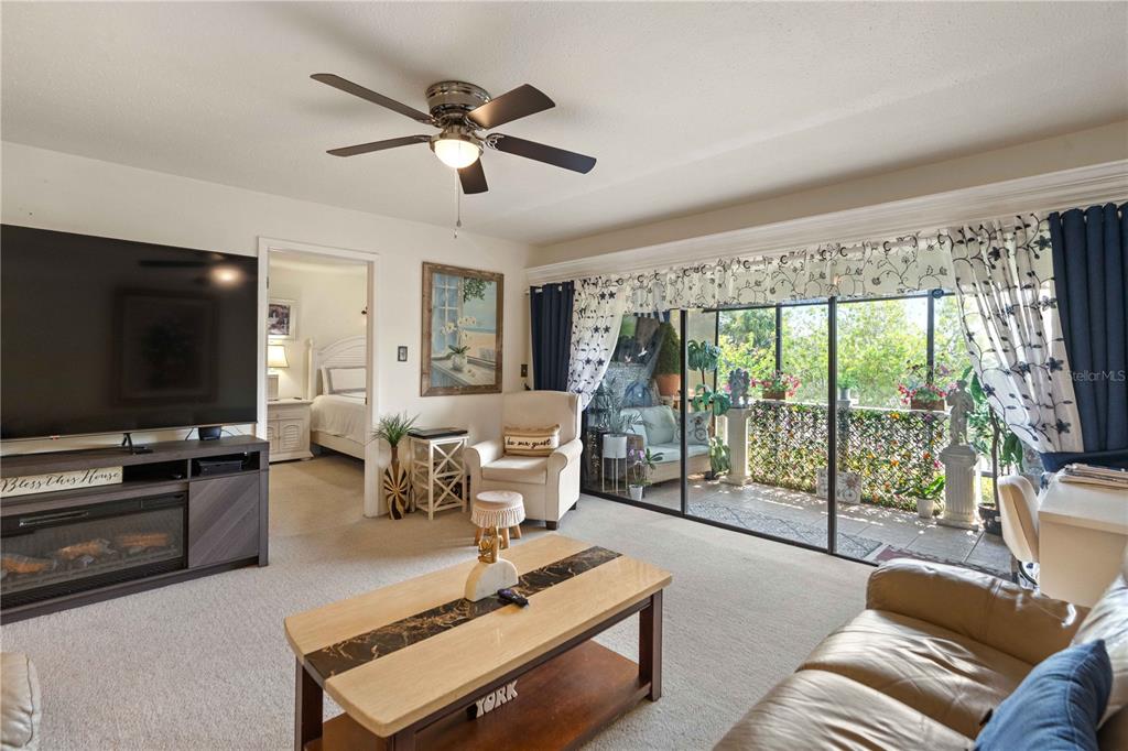 A kitchen features cream cabinets, a breakfast bar with stools, and a ceiling fan — 7623 RADCLIFFE CIRCLE UNIT 211A, PORT RICHEY, FL