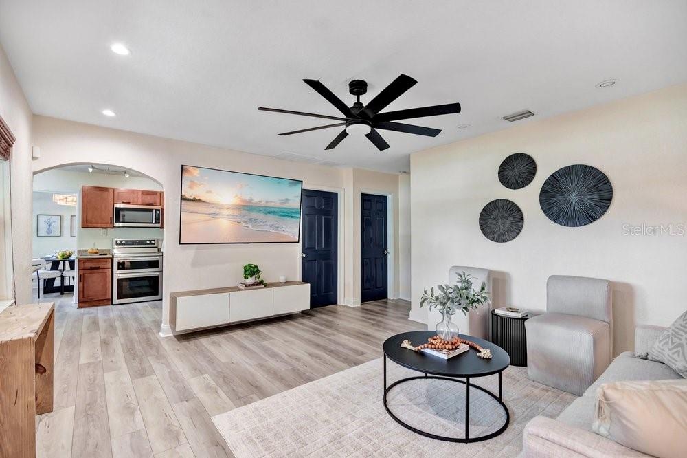 A living room with light wood flooring, a ceiling fan, and a wall-mounted television — 2829 LAKE MARGARET DRIVE, ORLANDO, FL