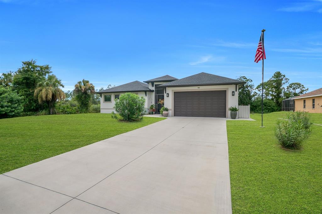 A single-story house with a concrete driveway, a two-car garage, and an American flag pole — 609 CLAYTON AVENUE, LEHIGH ACRES, FL