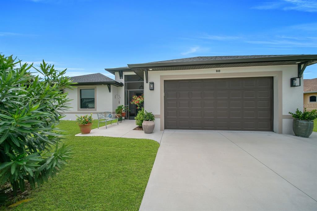 A single-story house with a concrete driveway, two-car garage, and a small front walkway — 609 CLAYTON AVENUE, LEHIGH ACRES, FL