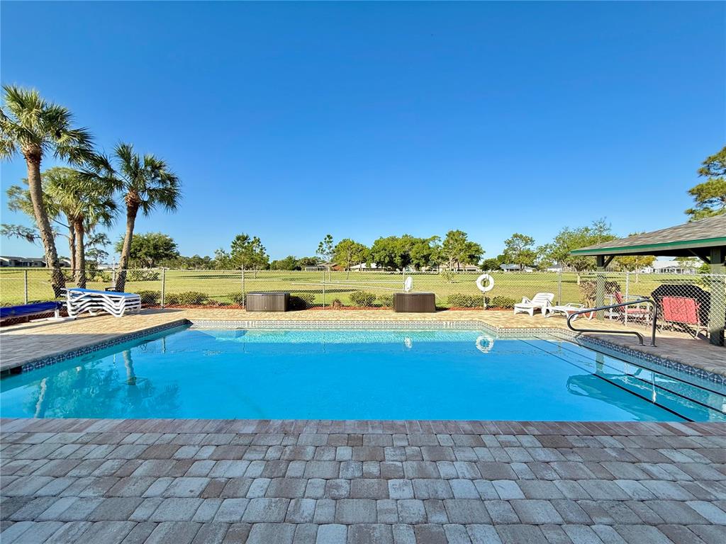 A rectangular swimming pool with a paver deck and a covered patio area — 3635 EDGEWATER DRIVE UNIT 3635, SEBRING, FL