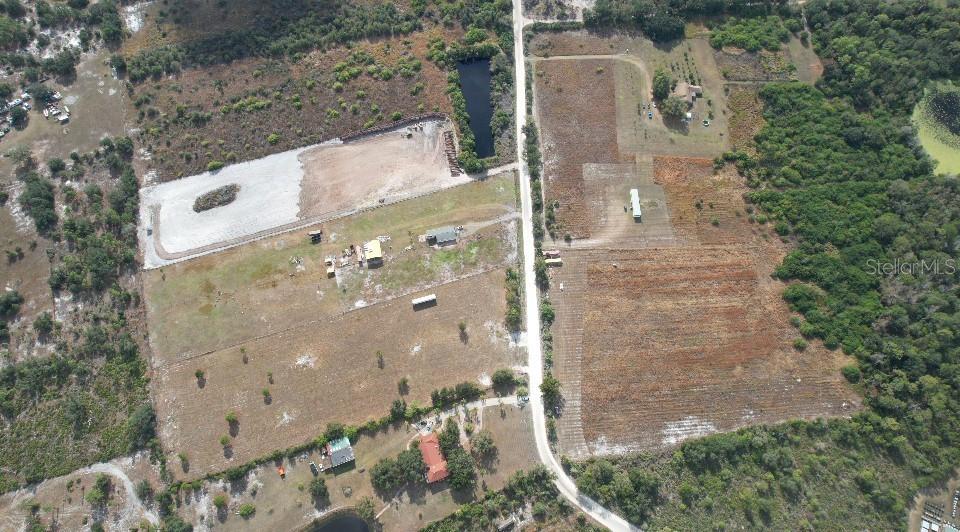 An aerial view shows rural land divided by a road with houses, ponds, and vegetation — 14451 SEMINOLE TRAIL, WIMAUMA, FL
