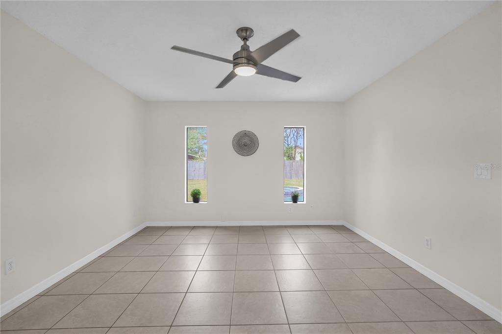 An empty room with light-colored walls, tiled flooring, a ceiling fan, and two narrow windows — 5165 FORMBY DRIVE, ORLANDO, FL