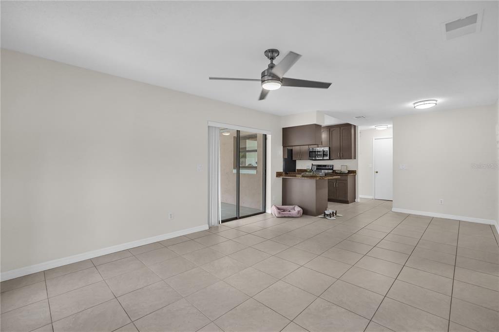 An open-concept living area features light tile flooring, a ceiling fan, and a kitchen — 5165 FORMBY DRIVE, ORLANDO, FL