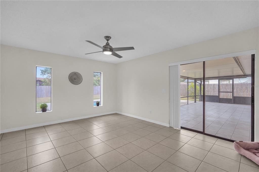 A living room with light tile flooring, a ceiling fan, two narrow windows, and sliding doors — 5165 FORMBY DRIVE, ORLANDO, FL