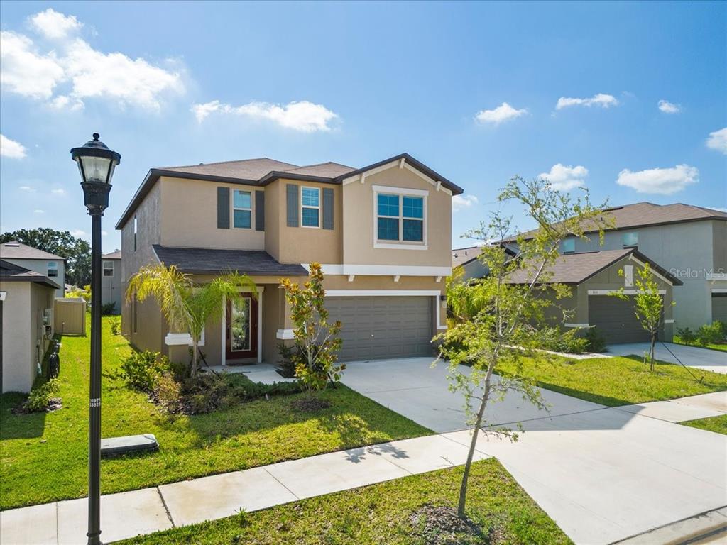 A two-story suburban house with a tan stucco exterior, a two-car garage, and a front lawn — 5517 APPLETON SHORE DRIVE, APOLLO BEACH, FL