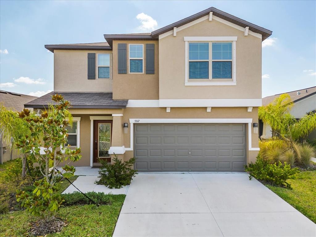 A two-story suburban house with a tan stucco exterior and a two-car garage — 5517 APPLETON SHORE DRIVE, APOLLO BEACH, FL