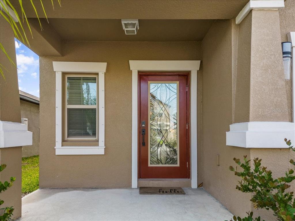A front entryway features a red door with a decorative glass insert and a window — 5517 APPLETON SHORE DRIVE, APOLLO BEACH, FL