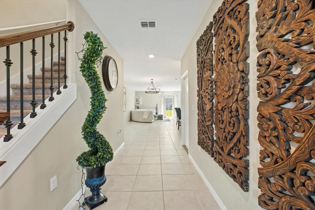 A tiled entryway features a staircase with iron railings, a spiral topiary, and wall art — 5517 APPLETON SHORE DRIVE, APOLLO BEACH, FL